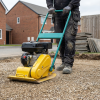 Construction worker compacting a gravel driveway with a 400mm petrol wacker plate compactor