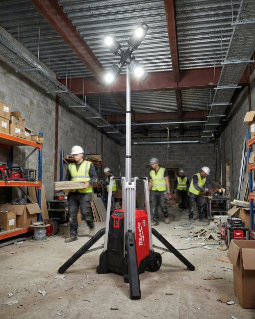Milwaukee MX FUEL LED lighting tower illuminating an indoor construction site with workers and materials
